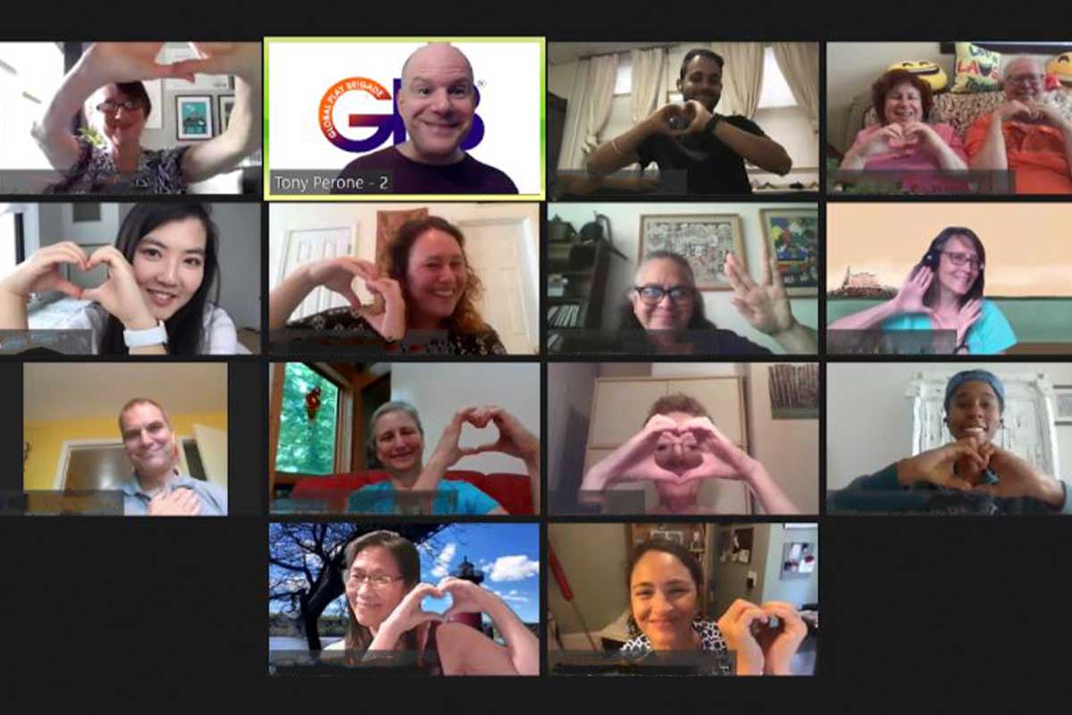 Screenshot of a virtual coaching meeting with 16 participants arranged in a grid. Everyone in this group offering is smiling and forming heart shapes with their hands, creating an improv feel. One participant has a highlighted section with text "Tony Perrone" and the number 2. A diverse array of individuals is visible.